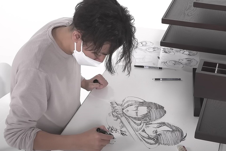 Hajime Isayama ilustrando uno de los escritorios de la subasta.